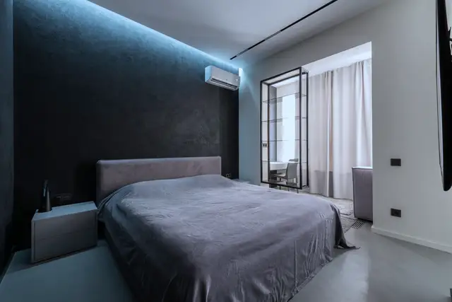 Wall-mounted ductless unit above a bed in a dim modern bedroom