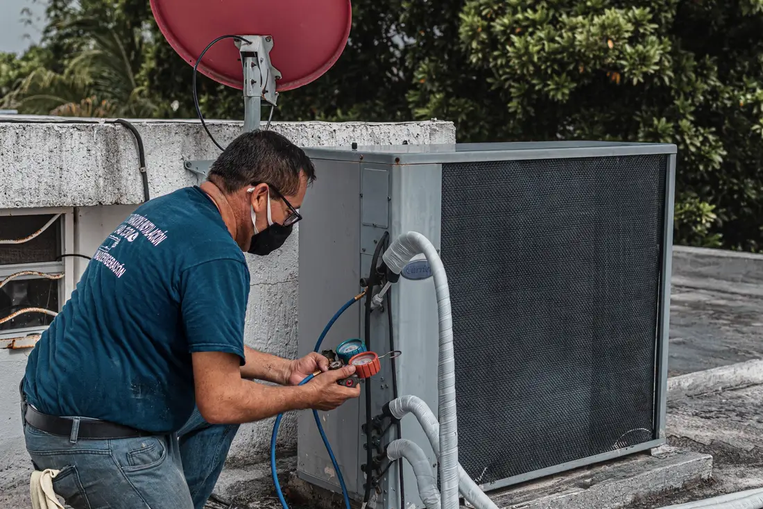 Technician reading manifold gauges while servicing an outdoor unit