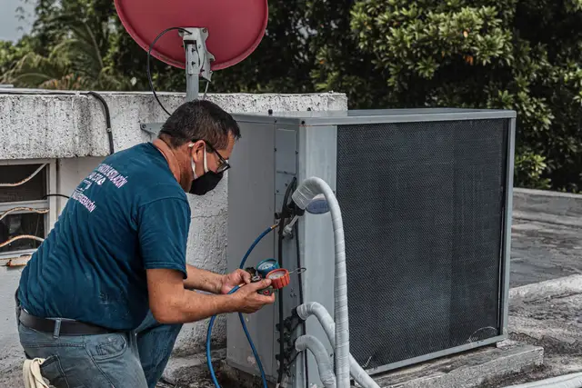 Technician reading pressure gauges while servicing heating equipment outdoors